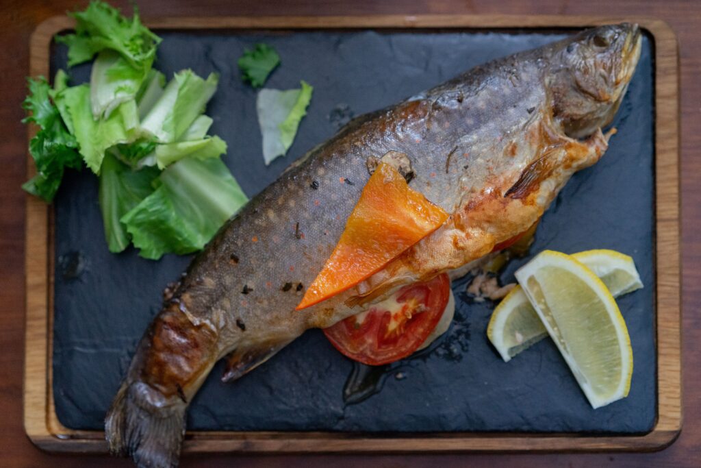 Peixe grelhado servido com limão e folhas, imagem ilustrativa