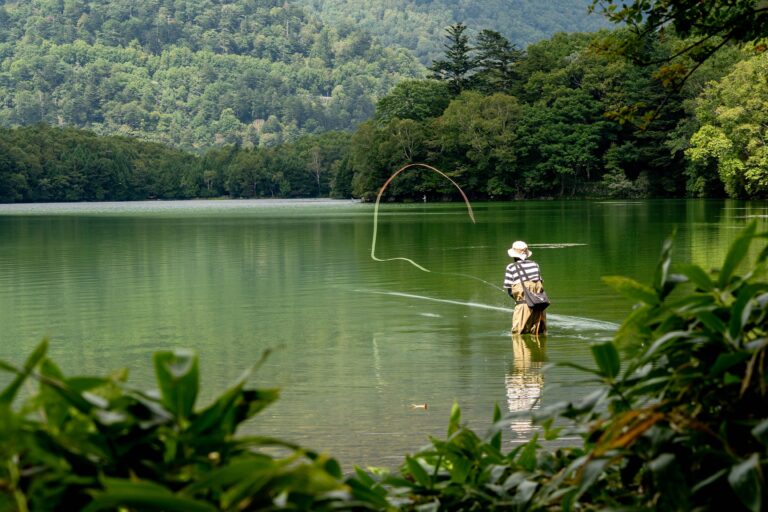 Pessoa pescando com mosca em lago de montanha, imagem ilustrativa de pesca de truta