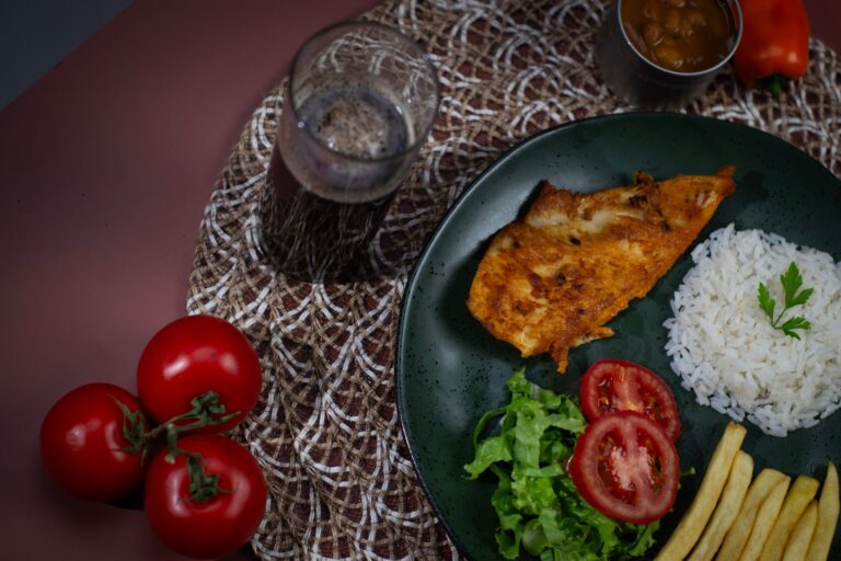 Prato com frango, arroz, salada e tomate, imagem ilustrativa de refeição econômica