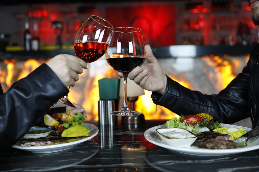Casal brindando com vinho durante jantar, imagem ilustrativa