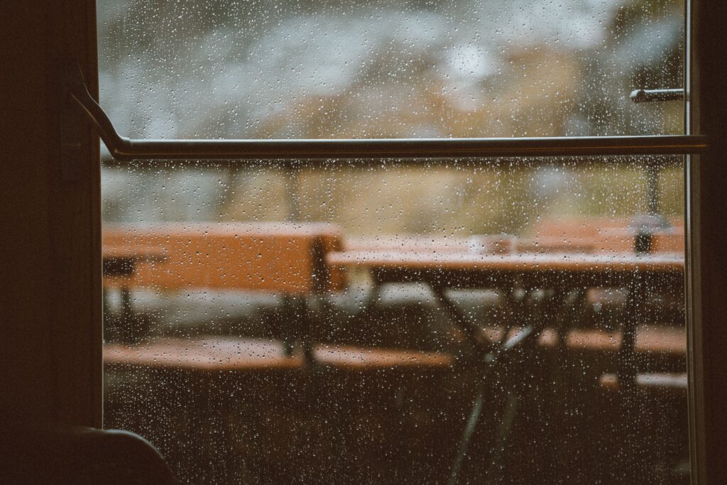 Gotas de chuva na janela, imagem ilustrativa para planejamento de passeio em Holambra em dia chuvoso