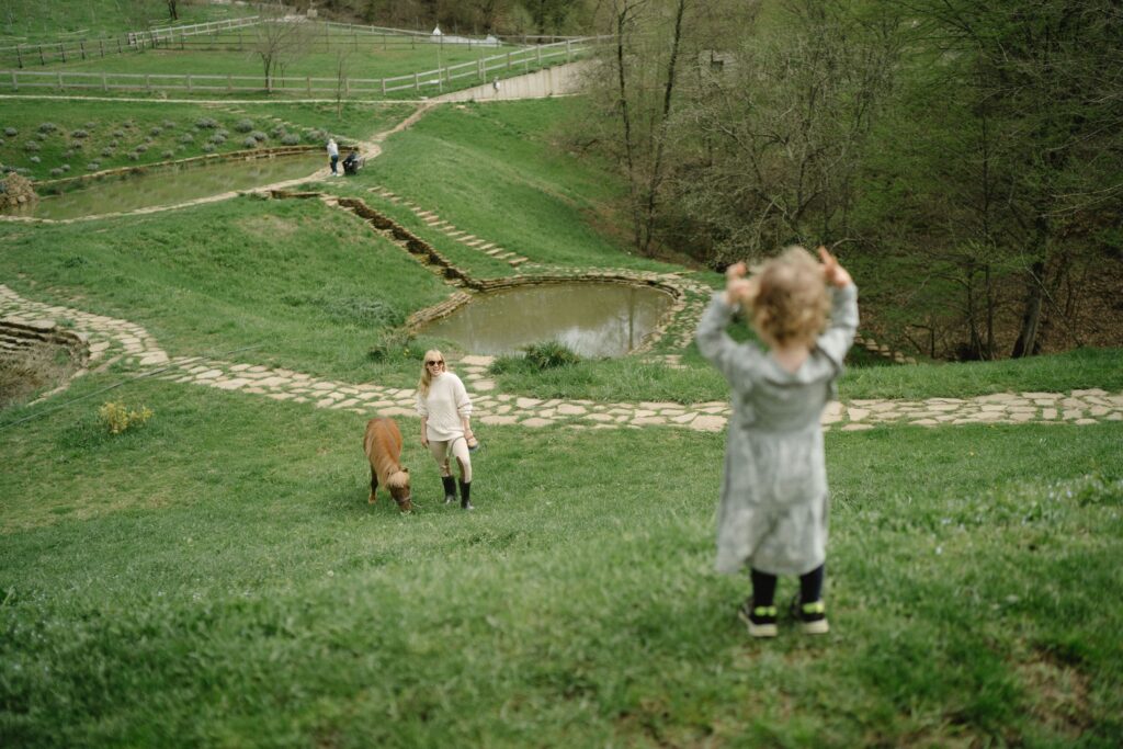 Mãe e criança perto de um pônei em ambiente rural, imagem ilustrativa