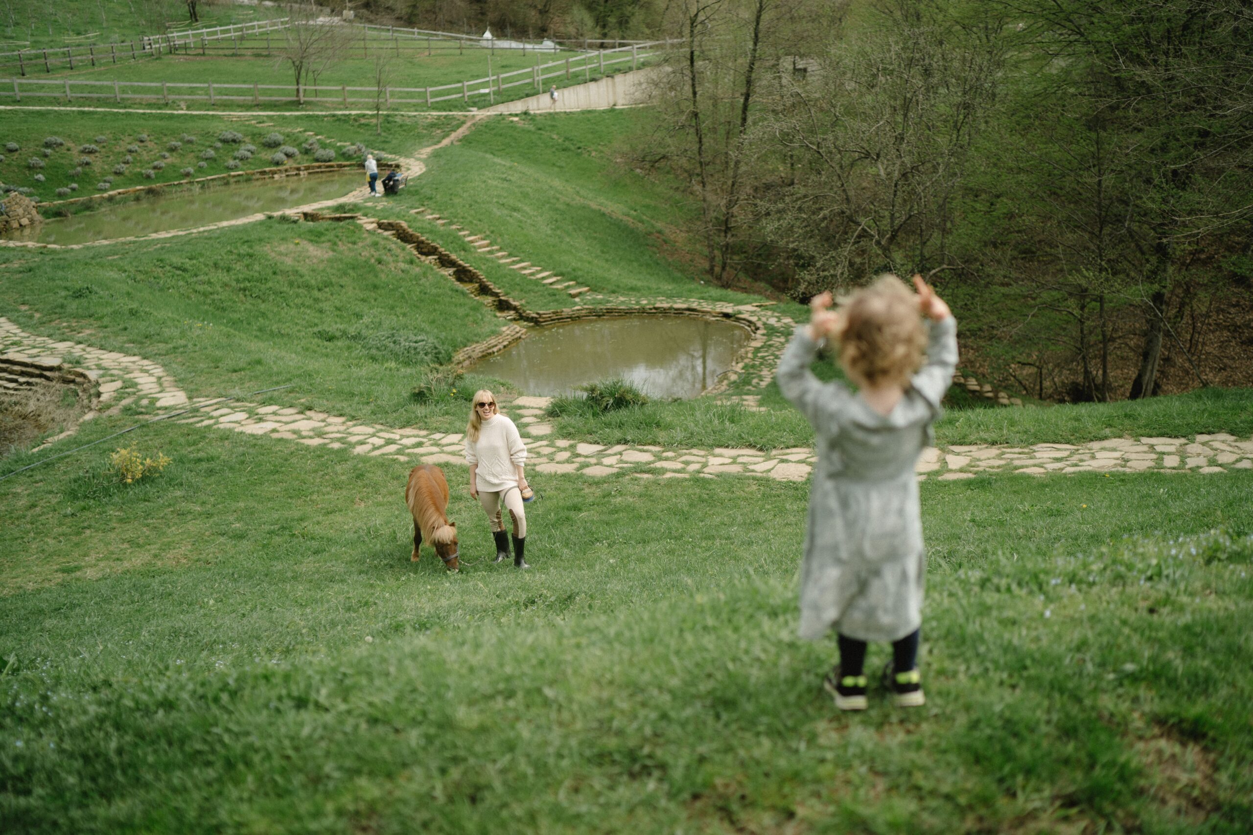 Mãe e criança perto de um pônei em ambiente rural, imagem ilustrativa