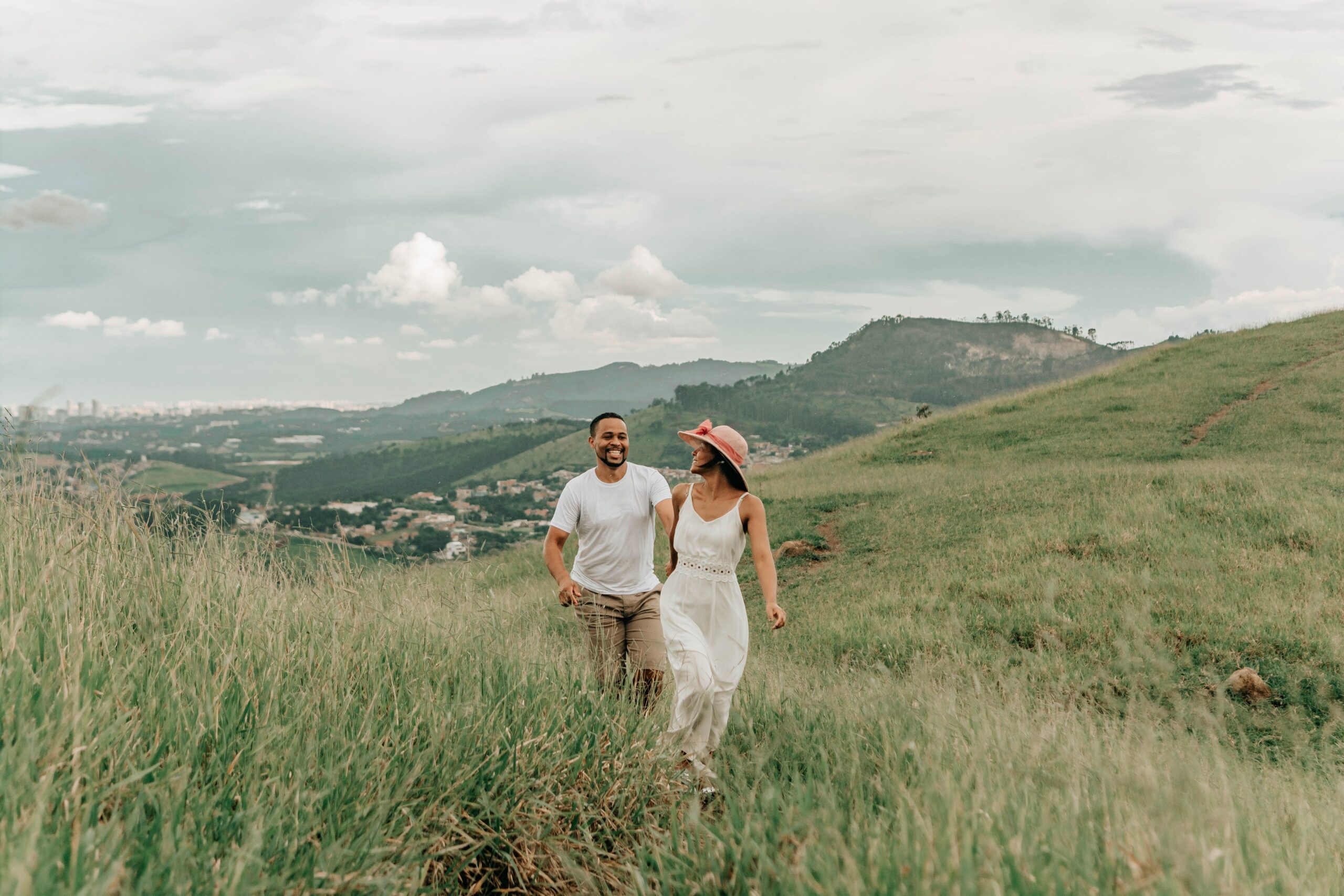 Casal caminhando em paisagem verde de montanha, imagem ilustrativa de viagem na primavera